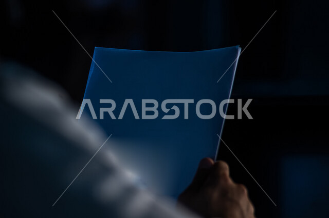 صورة مقربة لرجل عربي خليجي سعودي يحمل بيده اوراق ، بحث علمي ، خطط ومهام العمل ، وثيقة التوظيف ، رسائل خاصة ، قصص ومؤلفات