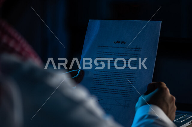صورة مقربة لرجل عربي خليجي سعودي يحمل بيده ورقة العرض المالي الخاصة بالعمل ،التكلفة الاجمالية والتفصيلية للمشروع ، مفهوم التوظيف والعمل