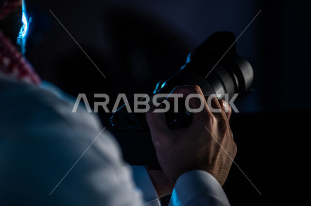 رجل عربي خليجي سعودي يحمل بيده كاميرا  احترافية ذات جودة ودقة عالية  ، مصور محترف بقوم بالتقاط الصور ، توثيق اللحظات،  التصوير الفوتوغرافي