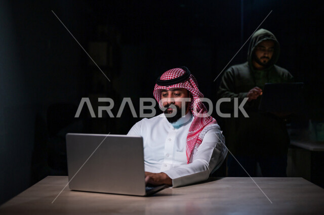 رجل عربي خليجي سعودي يستخدم حاسوبه المحمول، التعرض للإختراق والهجمات الالكترونية، الاختراق الأمني، اختراق حماية وأمن وخصوصية المستخدمين، الجرائم الالكترونية