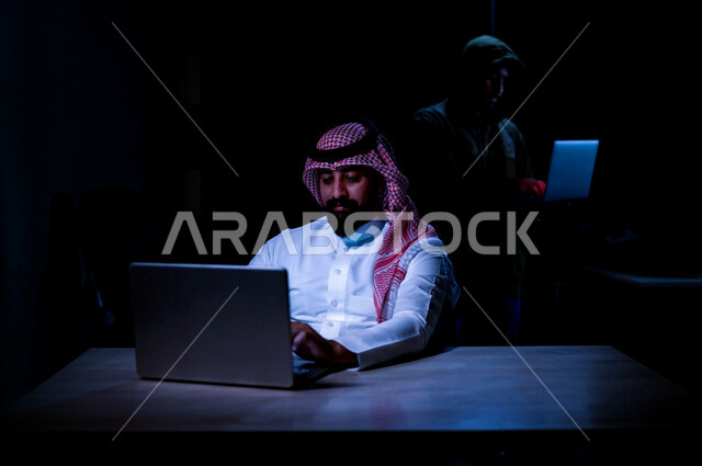 رجل عربي خليجي سعودي يستخدم حاسوبه المحمول، التعرض للإختراق والهجمات الالكترونية، الاختراق الأمني، اختراق حماية وأمن وخصوصية المستخدمين، الجرائم الالكترونية