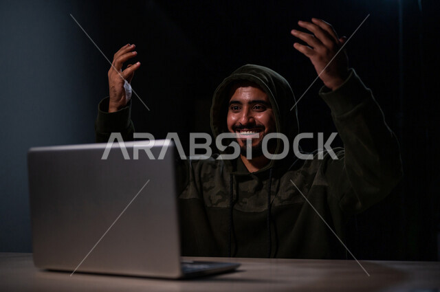 شاب عربي خليجي سعودي بايماءات وجه سعيدة، يعمل في مجال الهكر الغير قانوني، اختراق حماية وأمن وخصوصية المستخدمين، الجرائم الالكترونية
