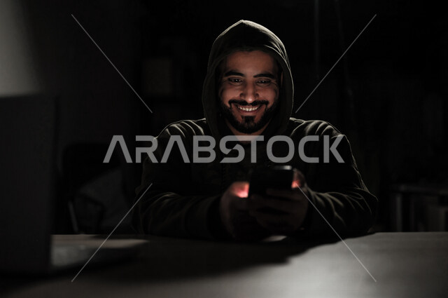 شاب عربي خليجي سعودي بايماءات وجه سعيدة، يعمل في مجال الهكر الغير قانوني، اختراق حماية وأمن وخصوصية المستخدمين، الجرائم الالكترونية