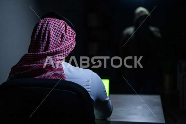 رجل عربي خليجي سعودي يستخدم حاسوبه المحمول، التعرض للإختراق والهجمات الالكترونية، الاختراق الأمني، اختراق حماية وأمن وخصوصية المستخدمين، الجرائم الالكترونية