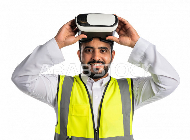 بورتريه لمهندس عربي خليجي سعودي يرتدي سترة خاصة بالعمل، ، يستعد للبس نظارة الواقع الافتراضي ، مشاهدة عناصر ثلاثية الابعاد، تصاميم افتراضية ،دمج تقنية الواقع الافتراضي في الهندسة المعمارية ،خلفية بيضاء
