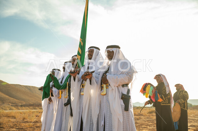 The concept of patriotism and belonging to the homeland, the anniversary of the founding of the first Saudi state in 1727 AD, a folklore performance troupe in the desert of the Kingdom, wearing the popular Najdi Ardah costume on the national occasion, celebrating the National Day by dancing with swords and beating drums, the day we started on February 22