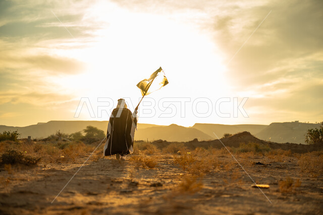 Pride and honor for the homeland, the anniversary of the founding of the first Saudi state 1727 AD, celebrating a distinguished national occasion, wearing the Central Region costume, the day we started on February 22, a picture from the back of a Saudi Gulf Arab man wearing a bisht and a golden agal raising the Kingdom’s flag at sunrise in the desert