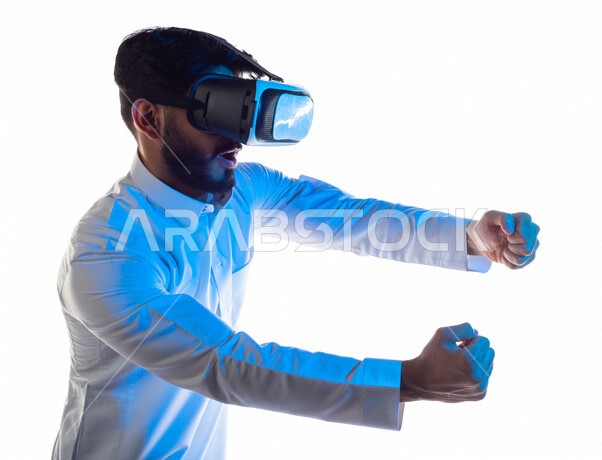 Portrait of a Saudi Arabian Gulf man wearing unique 3D virtual reality glasses, interacting with his hands with defensive martial arts games, virtual world games, virtual world simulation, technologies and games, white background