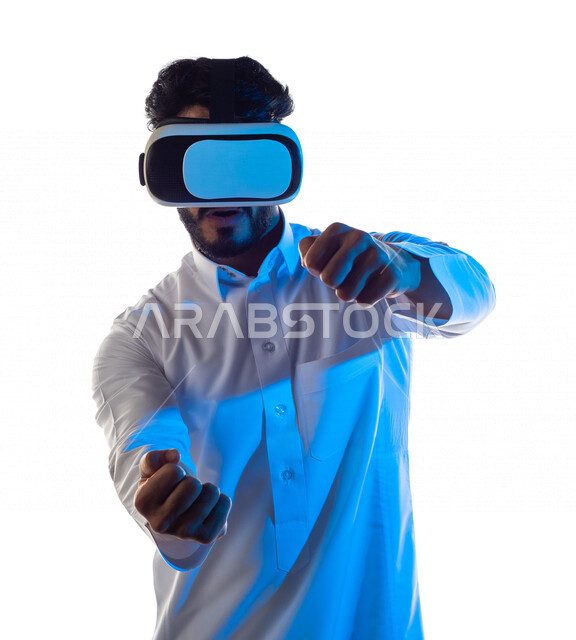 Portrait of a Saudi Arabian Gulf man wearing unique 3D virtual reality glasses, gestures and expressions that indicate focus in car driving games, fun and entertainment in virtual world games, simulation of the virtual world, white background