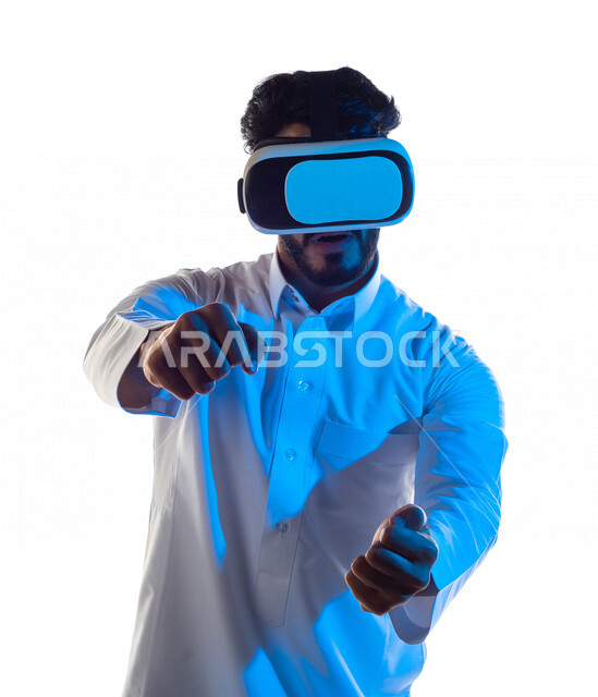 Portrait of a Saudi Arabian Gulf man wearing unique 3D virtual reality glasses, gestures and expressions that indicate focus in car driving games, fun and entertainment in virtual world games, simulation of the virtual world, white background