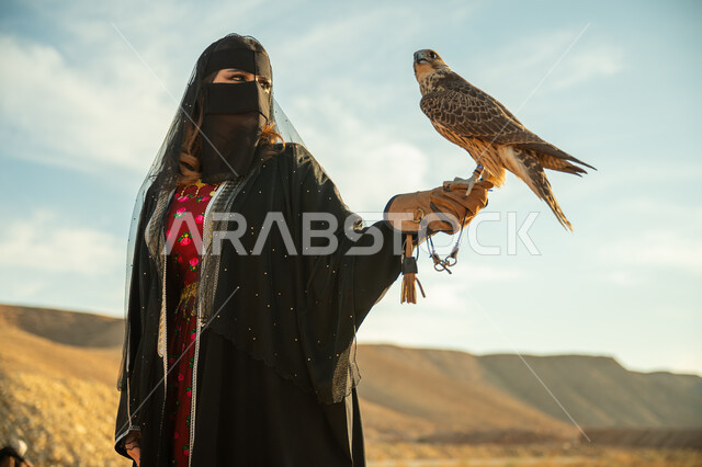 مفهوم الافتراس وحدة البصر, يوم بدينا 22 فبراير، مكانة الصقور في التاريخ السعودي ,تربية الطائر الجارح في السعودية, ذكرى تاسيس الدوله السعوديه الاولى 1727م, امرأة عربية خليجية سعودية ترتدي البشت النسائي السعودي و البرقع يقف على يدها الصقر في الصحراء