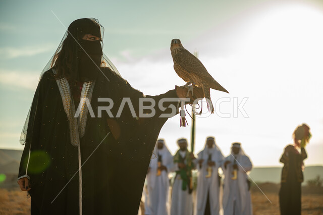 مفهوم الافتراس وحدة البصر, مكانة الصقور في التاريخ السعودي, تربية الطائر الجارح، ذكرى تاسيس الدوله السعوديه الاولى 1727م, يوم بدينا 22 فبراير، امرأة عربية خليجية سعودية ترتدي البشت النسائي السعودي و البرقع يقف على يدها الصقر, خلفية العرضة النجدية في الصحراء