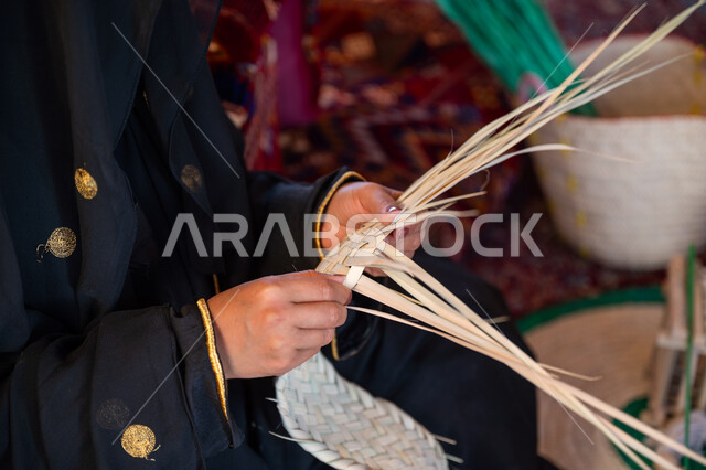 يوم بدينا 22 فبراير، الفخر بالتراث السعودي العريق، صورة مقربة امرأة عربية خليجية سعودية ترتدي الزي الشعبي التقليدي تقوم بصناعة الحصير، عرض المنتجات المحليه الوطنيه، حرفة يدوية شعبية، ذكرى تأسيس الدولة السعودية الأولى 1727 م