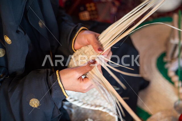 يوم بدينا 22 فبراير، الفخر بالتراث السعودي العريق، صورة مقربة امرأة عربية خليجية سعودية ترتدي الزي الشعبي التقليدي تقوم بصناعة الحصير، عرض المنتجات المحليه الوطنيه، حرفة يدوية شعبية، ذكرى تأسيس الدولة السعودية الأولى 1727 م