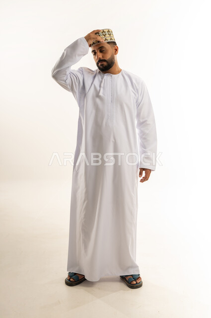 الاحساس بالشقيقة والصداع النصفي, الشعور بالإرهاق وفقدان التركيز, بورتريه لرجل عربي خليجي عماني يرتدي الدشداشة والكمة يضع يده على رأسه يغمض عينيه بإيماءات وجع الرأس, النسيان ومحاولة تذكر شيء ما, الجسم بالطول الكامل, خلفية بيضاء