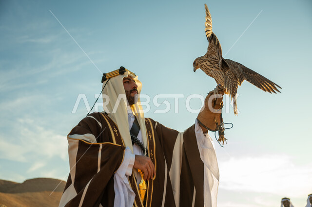 يوم بدينا 22 فبراير، العناية بتربية الطيور و تدريبها, مكانة الصقور في التاريخ السعودي, صورة مقربة لرجل عربي خليجي سعودي يرتدي الغترة والبشت يحمل على يده طائر الصقر بتعابير الفخر, ذكرى تاسيس الدوله السعوديه الاولى 1727 م, مناسبة وطنيه شعبيه