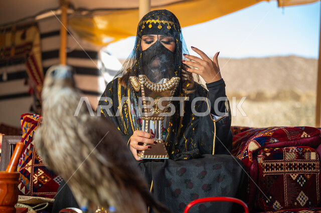 الافتراس وحدة البصر, اتباع عادات وتقاليد دول الخليج بالتبخر، مكانة الصقور في التاريخ السعودي, ذكرى تأسيس الدوله السعوديه الأولى 1727م, يوم بدينا 22 فبراير، امرأة عربية خليجية سعودية ترتدي الزي الشعبي للأعياد الوطنية والبرقع تحمل بيدها المبخرة وأمامها الصقر