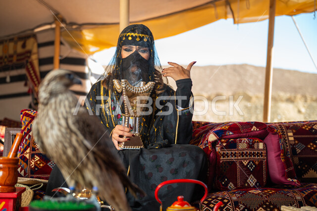 ذكرى تأسيس الدوله السعوديه الأولى 1727م, يوم بدينا 22 فبراير، الافتراس وحدة البصر, اتباع عادات وتقاليد دول الخليج بالتبخر، مكانة الصقور في التاريخ السعودي, امرأة عربية خليجية سعودية ترتدي الزي الشعبي للأعياد الوطنية والبرقع تحمل بيدها المبخرة وأمامها الصقر