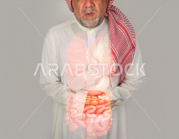 بورتريه لرجل عربي سعودي كبير بالسن يشكو من آلام في الأمعاء الداخلية , صحة وأطباء , حالة مرضية , ايماءات وجه تدل على الألم والتعب الشديد , خلفية رمادية.