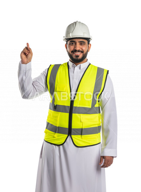 بورتريه لمهندس عربي خليجي سعودي يرتدي الخوذة والسترة الخاصة بالعمل ،يشير باصبع السبابة لهدف ما، الاشارة لموقع وبناء ،خلفية بيضاء