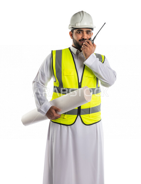 بورتريه لمهندس عربي خليجي سعودي يرتدي خوذة و سترة خاصة بالعمل، يحمل بيده مخطط البناء ، يستخدم جهاز اتصال لاسلكي ، اشراف ومتابعة العمل ،اعطاء اوامر خاصة بالعمل ، مهن و وظائف ، ادارة المشاريع المعمارية الهندسية