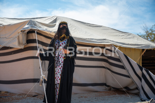 يوم بدينا  22 فبراير، ذكرى تأسيس الدولة السعودية الأولى في 1727م، الشموخ والاعتزاز والفخر، امرأة عربية خليجية سعودية ترتدي العباءة والبرقع تقف بجوار الخيمة في الصحراء, إظهار حب الوطن والانتماء إليه، ارتداء الزي الشعبي في المناسبة الوطنية