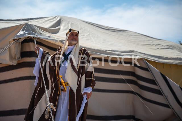 ذكرى تأسيس الدولة السعودية الأولى في 1727م، الشموخ والاعتزاز والفخر، رجل عربي خليجي سعودي يرتدي العقال الذهبي والبشت يقف بجوار الخيمة في الصحراء, يوم بدينا  22 فبراير، ارتداء الزي الشعبي في المناسبة الوطنية، إظهار حب الوطن والانتماء إليه