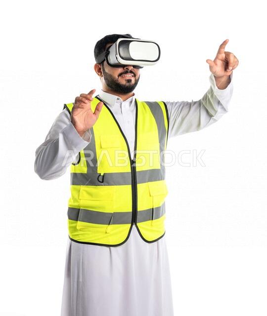 بورتريه لمهندس عربي خليجي سعودي يرتدي سترة خاصة بالعمل و نظارة الواقع الافتراضي ، يشير باصبع السبابة لهدف معين ، استخدام تقنية الواقع الافتراضي في الهندسة المعمارية، خلفية بيضاء