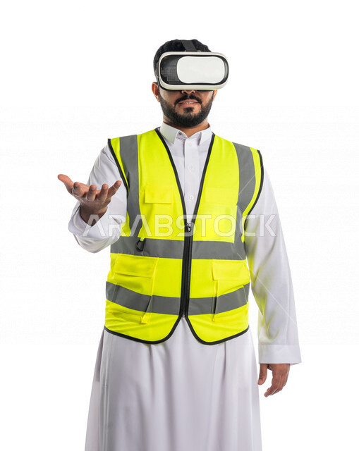 بورتريه لمهندس عربي خليجي سعودي يرتدي سترة خاصة بالعمل و نظارة الواقع الافتراضي ،يحمل عنصر فوق يده، استخدام  تقنية الواقع الافتراضي في الهندسة المعمارية ، خلفية بيضاء