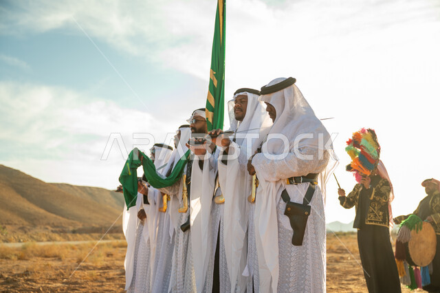 A band celebrating the National Day with sword dancing and drumming, the anniversary of the founding of the first Saudi state in 1727 AD, traditional folklore shows in one of the desert areas of the Kingdom, the concept of love of the homeland and belonging to it, the day we started on February 22, wearing the popular Najdi Ardah costume on a national occasion
