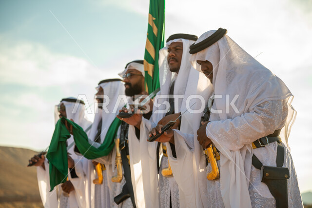 ارتداء زي العرضة النجدية الشعبية في مناسبة وطنية، فرقة عروض الفلكلور التراثي في احدى المناطق الصحراوية بالمملكة، مفهوم حب الوطن والانتماء إليه، يوم بدينا ٢٢ فبراير، ذكرى تأسيس الدوله السعوديه الأولى ١٧٢٧ م، الاحتفال بالعيد الوطني بالرقص بالسيوف وقرع الطبول 