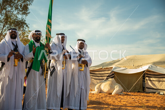 ارتداء زي العرضة النجدية الشعبية في مناسبة وطنية، فرقة عروض الفلكلور التراثي في احدى المناطق الصحراوية بالمملكة، مفهوم حب الوطن والانتماء إليه، يوم بدينا ٢٢ فبراير، ذكرى تأسيس الدوله السعوديه الأولى ١٧٢٧ م، الاحتفال بالعيد الوطني بالرقص بالسيوف وقرع الطبول 