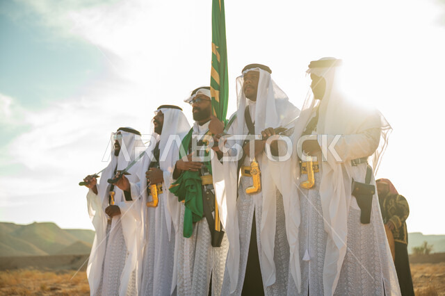 ارتداء زي العرضة النجدية الشعبية في مناسبة وطنية، فرقة عروض الفلكلور التراثي في احدى المناطق الصحراوية بالمملكة، مفهوم حب الوطن والانتماء إليه، يوم بدينا ٢٢ فبراير، ذكرى تأسيس الدوله السعوديه الأولى ١٧٢٧ م، الاحتفال بالعيد الوطني بالرقص بالسيوف وقرع الطبول 
