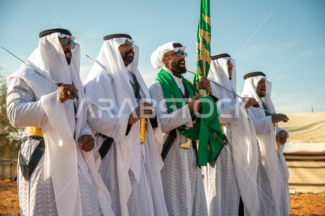 ارتداء زي العرضة النجدية الشعبية في مناسبة وطنية، فرقة عروض الفلكلور التراثي في احدى المناطق الصحراوية بالمملكة، مفهوم حب الوطن والانتماء إليه، يوم بدينا ٢٢ فبراير، ذكرى تأسيس الدوله السعوديه الأولى ١٧٢٧ م، الاحتفال بالعيد الوطني بالرقص بالسيوف وقرع الطبول 