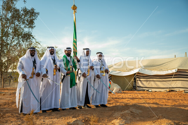فرقة عروض الفلكلور التراثي في احدى المناطق الصحراوية بالمملكة، ارتداء زي العرضة النجدية الشعبية في مناسبة وطنية، مفهوم حب الوطن والانتماء إليه، يوم بدينا ٢٢ فبراير، ذكرى تأسيس الدوله السعوديه الأولى ١٧٢٧ م، الاحتفال بالعيد الوطني بالرقص بالسيوف وقرع الطبول 