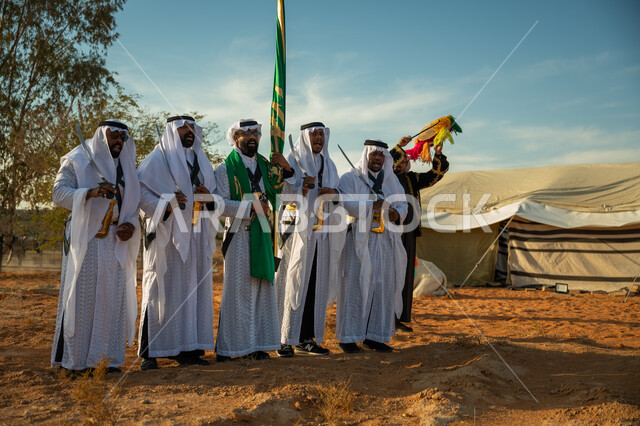 ارتداء زي العرضة النجدية الشعبية في مناسبة وطنية، فرقة عروض الفلكلور التراثي في احدى المناطق الصحراوية بالمملكة، مفهوم حب الوطن والانتماء إليه، يوم بدينا ٢٢ فبراير، ذكرى تأسيس الدوله السعوديه الأولى ١٧٢٧ م، الاحتفال بالعيد الوطني بالرقص بالسيوف وقرع الطبول 