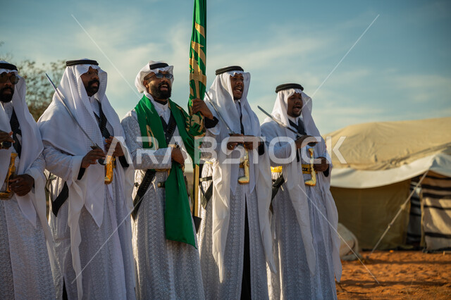 A folklore performance group in one of the desert regions of the Kingdom, wearing the popular Najdi Ardah costume on a national occasion, the concept of love of the homeland and belonging to it, the day we started February 22, the anniversary of the founding of the first Saudi state 1727 AD, celebrating the National Day by dancing with swords and beating drums