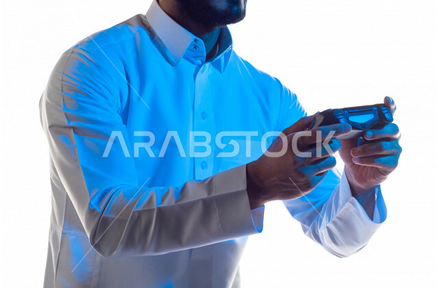 صورة مقربة لرجل عربي خليجي سعودي ، يمسك عصا التحكم و يلعب بألعاب الفيديو ، المتعة و التسلية بألعاب الفيديو و ألعاب العالم الافتراضي ، ألعاب البلايستيشن الترفيهية ، تقنيات و ألعاب ، خلفية بيضاء