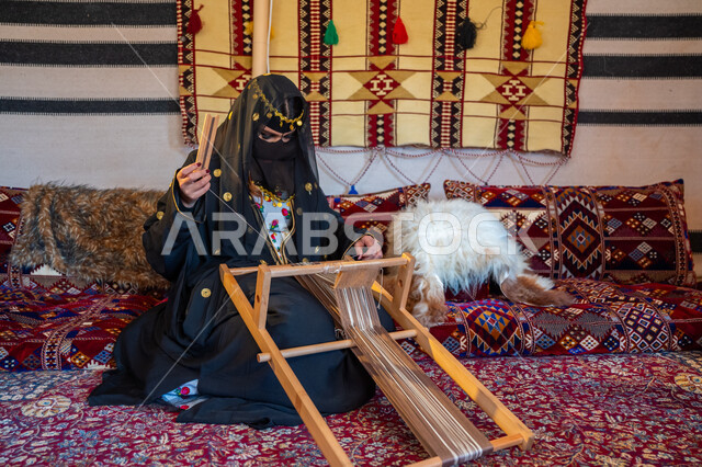 حرفة يدوية تاريخية, منتج محلي وطني، ارتداء الزي الشعبي في المناسبة الوطنية، امرأة عربية خليجية سعودية ترتدي العباءة والبرقع تجلس داخل الخيمة تقوم بحياكة وغزل الأنسجة والقماش, مهنة تقليدية قديمة, يوم بدينا  22 فبراير، ذكرى تأسيس الدولة السعودية الأولى في 1727م