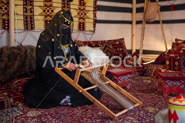 مهنة تقليدية قديمة, يوم بدينا  22 فبراير، ارتداء الزي الشعبي في المناسبة الوطنية، امرأة عربية خليجية سعودية ترتدي العباءة والبرقع تجلس داخل الخيمة تقوم بحياكة وغزل الأنسجة والقماش, حرفة يدوية تاريخية, منتج محلي وطني، ذكرى تأسيس الدولة السعودية الأولى في 1727م