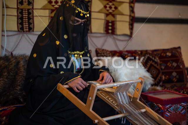 مهنة تقليدية قديمة, يوم بدينا  22 فبراير، ارتداء الزي الشعبي في المناسبة الوطنية، امرأة عربية خليجية سعودية ترتدي العباءة والبرقع تجلس داخل الخيمة تقوم بحياكة وغزل الأنسجة والقماش, حرفة يدوية تاريخية, منتج محلي وطني، ذكرى تأسيس الدولة السعودية الأولى في 1727م