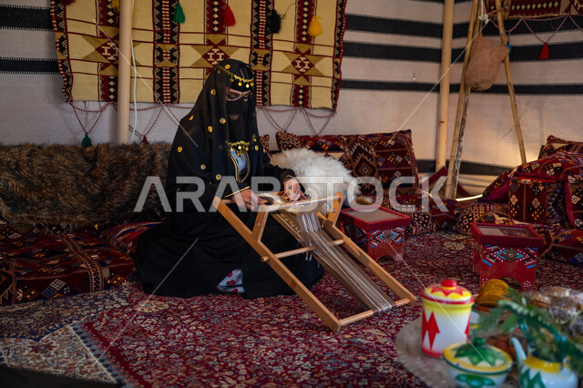 مهنة تقليدية قديمة, يوم بدينا  22 فبراير، ارتداء الزي الشعبي في المناسبة الوطنية، امرأة عربية خليجية سعودية ترتدي العباءة والبرقع تجلس داخل الخيمة تقوم بحياكة وغزل الأنسجة والقماش, حرفة يدوية تاريخية, منتج محلي وطني، ذكرى تأسيس الدولة السعودية الأولى في 1727م