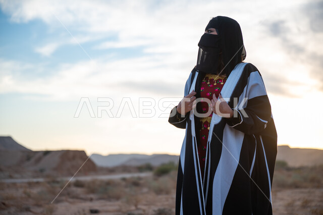 الشعور بالفخر للانتماء للوطن, ذكرى تأسيس الدولة السعودية الأولى 1727 م، يوم بدينا 22 فبراير، العناية والاهتمام بالمظهر الخارجي، ارتداء زي المنطقة الوسطى في المناسبة الوطنية، امرأة خليجية عربية سعودية ترتدي العباءة والبرقع الاسود تقف في الطبيعة الصحراوية