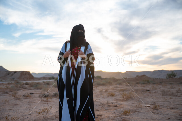 ذكرى تأسيس الدولة السعودية الأولى 1727 م، يوم بدينا 22 فبراير، العناية والاهتمام بالمظهر الخارجي، ارتداء زي المنطقة الوسطى في المناسبة الوطنية، امرأة خليجية عربية سعودية ترتدي العباءة والبرقع الاسود تقف في الطبيعة الصحراوية، الفخر والاعتزاز بالانتماء للوطن