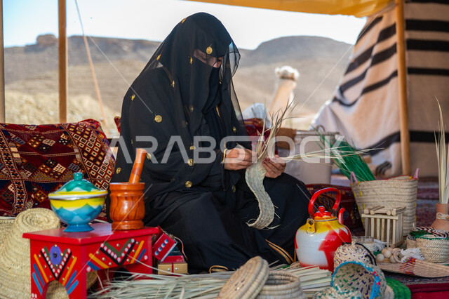 يوم بدينا 22 فبراير، ارتداء الزي الشعبي في المناسبة الوطنية، حرفة يدوية تقليدية, ذكرى تأسيس الدولة السعودية الأولى في 1727م، امرأة عربية خليجية سعودية ترتدي النقاب والعباءة تجلس في خيمة في الصحراء تقوم بجدل سعائف الخوص, استخدام أوراق النخيل المجففة في صناعة السلل