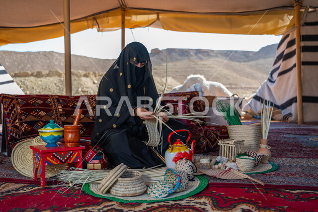 حرفة يدوية تقليدية, ذكرى تأسيس الدولة السعودية الأولى في 1727م، امرأة عربية خليجية سعودية ترتدي النقاب والعباءة تجلس في خيمة في الصحراء تقوم بجدل سعائف الخوص, ارتداء الزي الشعبي في المناسبة الوطنية، يوم بدينا 22 فبراير، استخدام أوراق النخيل المجففة في صناعة السلل