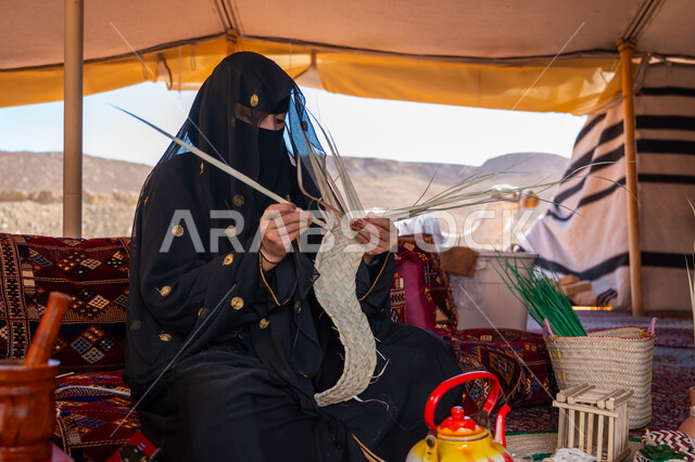 ارتداء الزي الشعبي في المناسبة الوطنية، حرفة يدوية تقليدية, ذكرى تأسيس الدولة السعودية الأولى في 1727م، امرأة عربية خليجية سعودية ترتدي النقاب والعباءة تجلس في خيمة في الصحراء تقوم بجدل سعائف الخوص, يوم بدينا 22 فبراير، استخدام أوراق النخيل المجففة في صناعة السلل