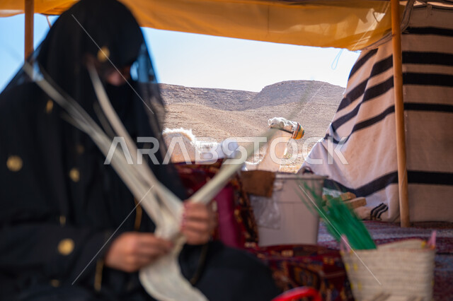 ذكرى تأسيس الدولة السعودية الأولى في 1727م، صورة مقربة لامرأة عربية خليجية سعودية ترتدي النقاب والعباءة تجلس في خيمة في الصحراء تقوم بجدل سعائف الخوص, حرفة يدوية تقليدية, يوم بدينا 22 فبراير، ارتداء الزي الشعبي في المناسبة الوطنية، استخدام أوراق النخيل المجففة في صناعة السلل