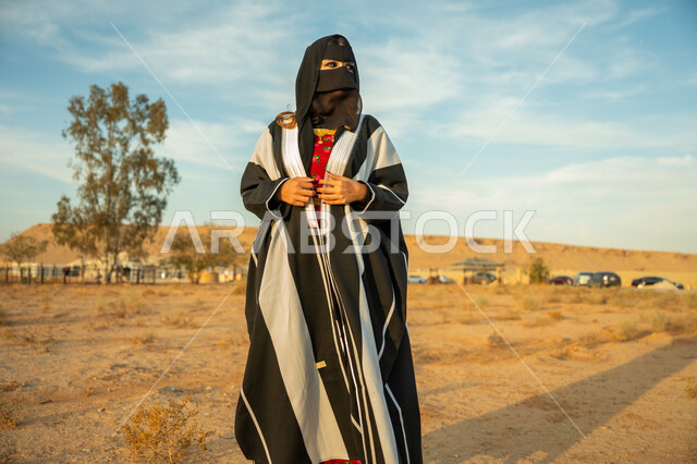 The day we started is February 22, interest and care for the external appearance, wearing the central region costume on the national occasion, a Saudi Arabian Gulf woman wearing the Saudi women's bisht and burqa standing on the soft golden sands of the desert, the anniversary of the founding of the first Saudi state 1727 AD, expressions of pride and confidence