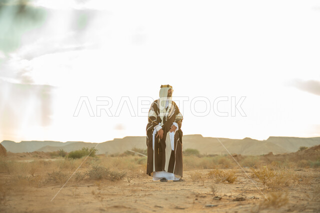 اظهار الولاء و التفاني للبلاد, ذكرى تاسيس الدوله السعوديه الاولى 1727 م, يوم بدينا 22 فبراير, مفهوم حب الوطن و الانتماء اليه, مناسبة شعبيه وطنيه, رجل عربي خليجي سعودي يرتدي الغترة والبشت يتجول في الصحراء و ينظر الى شيء ما, خلفية الصحراء